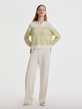 A lady wears a striped top and wide leg pants.